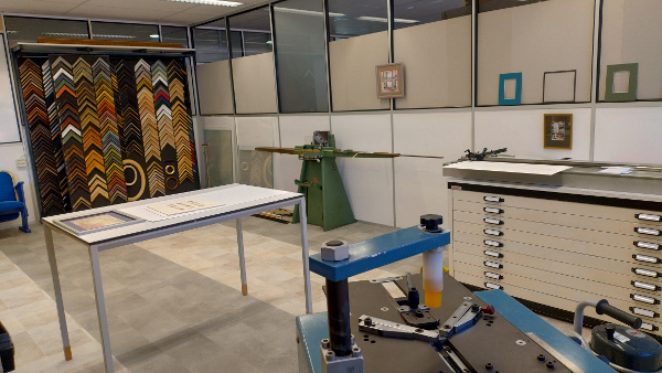 Een aantal machines in het inlijst atelier; o.a. verstek nietmachine, verstek stans en collectie met lijsten.
